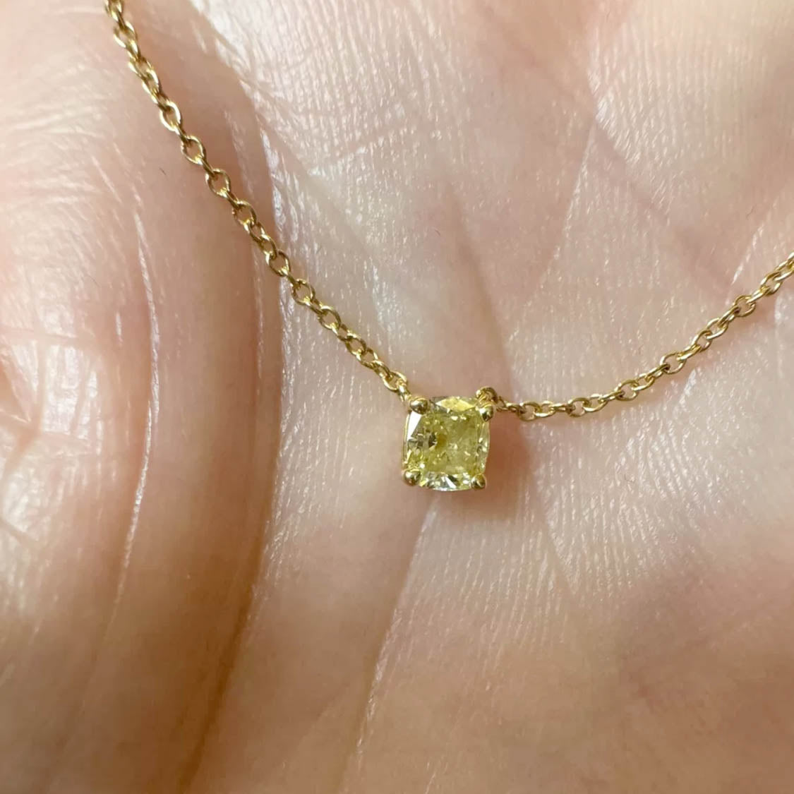 0.3ct cushion cut yellow diamond nectlace in 18k gold on hand