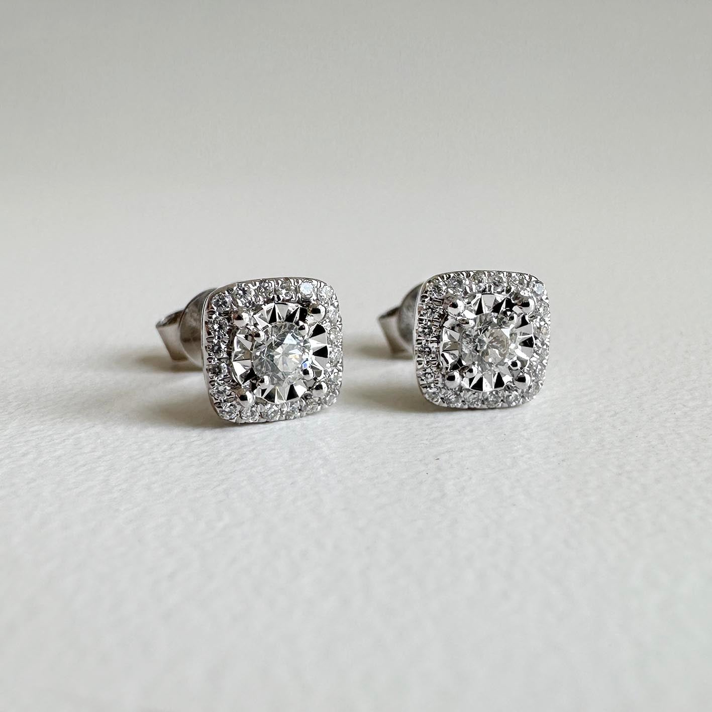 0.3ct cushion diamond halo earrings in 18k white gold on table