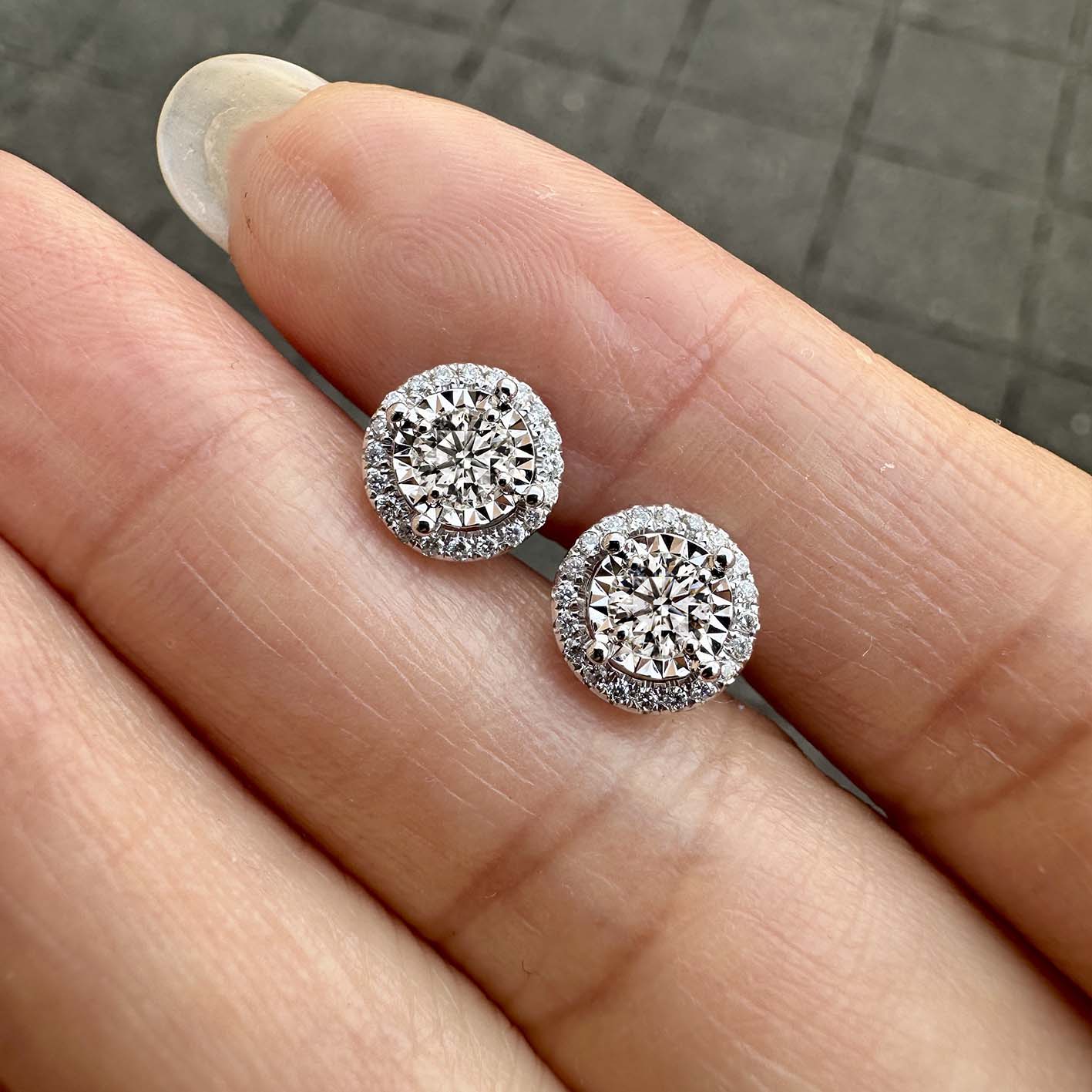 embrace 0.5ct round diamond halo earrings in 18k white gold on hand