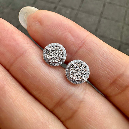 embrace 0.5ct round diamond halo earrings in 18k white gold on hand