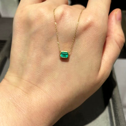 bezel set emerald necklace in 18k gold on hand