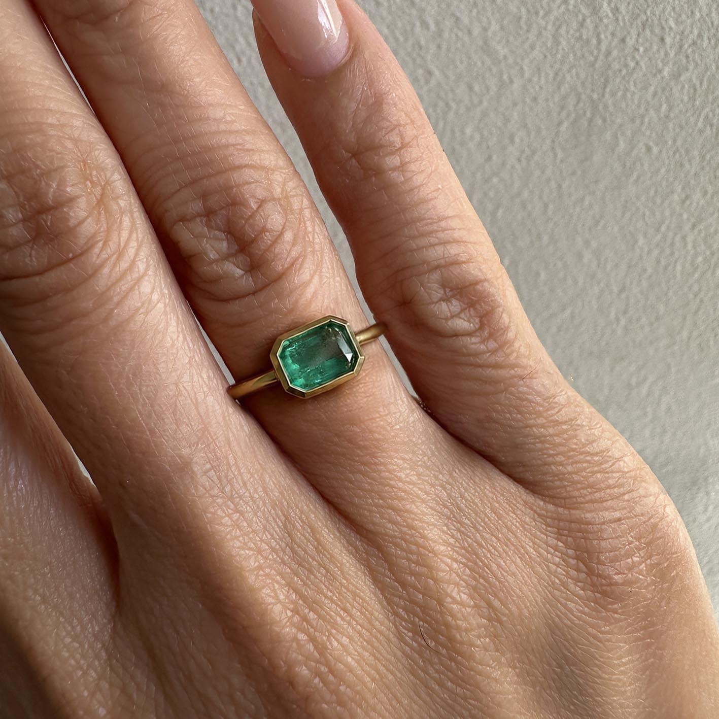1.0ct step cut emerald ring in 18k gold on model