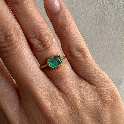 1.0ct step cut emerald ring in 18k gold on model