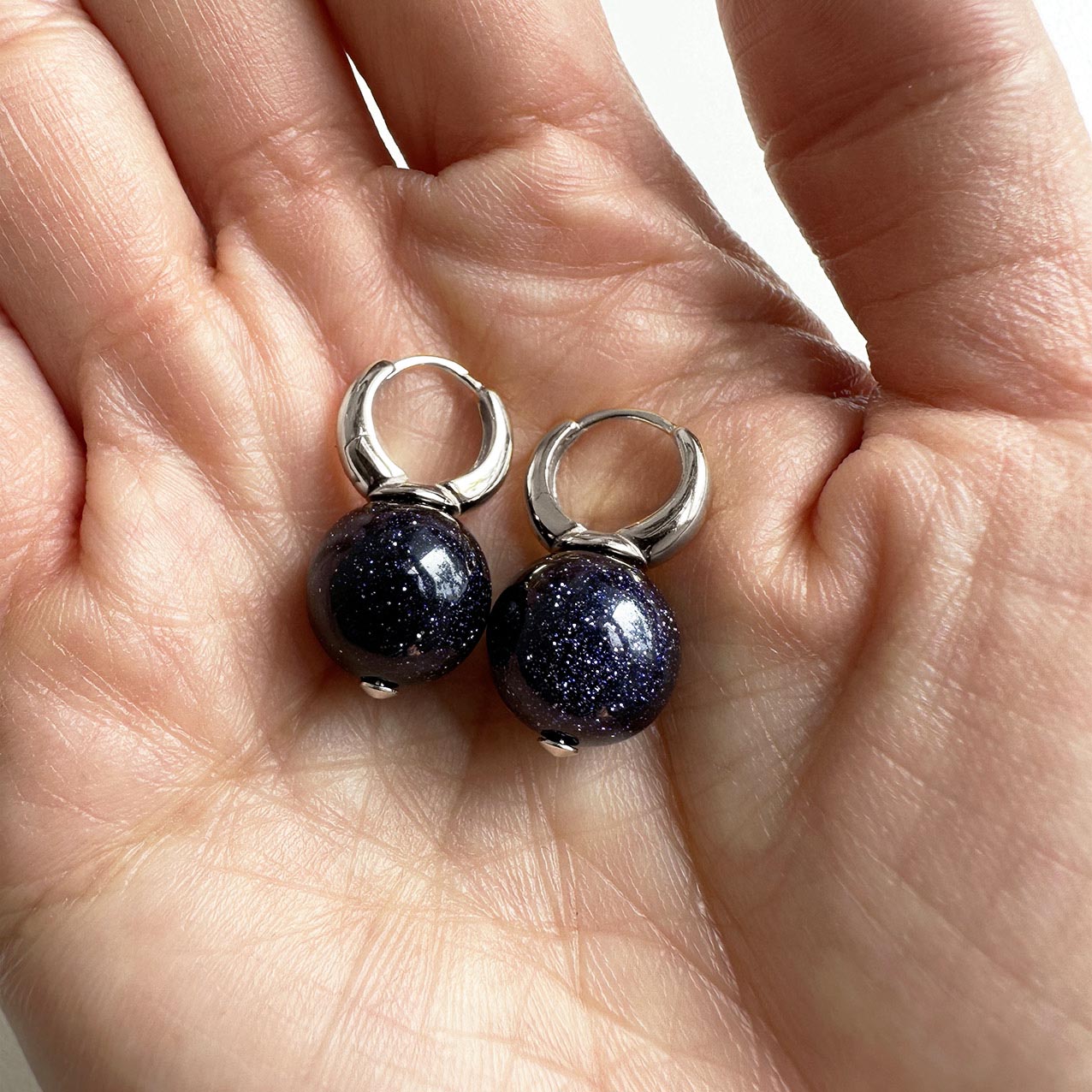 jullie blue sand ball earrings in 18k white gold plated sterling silver on hand