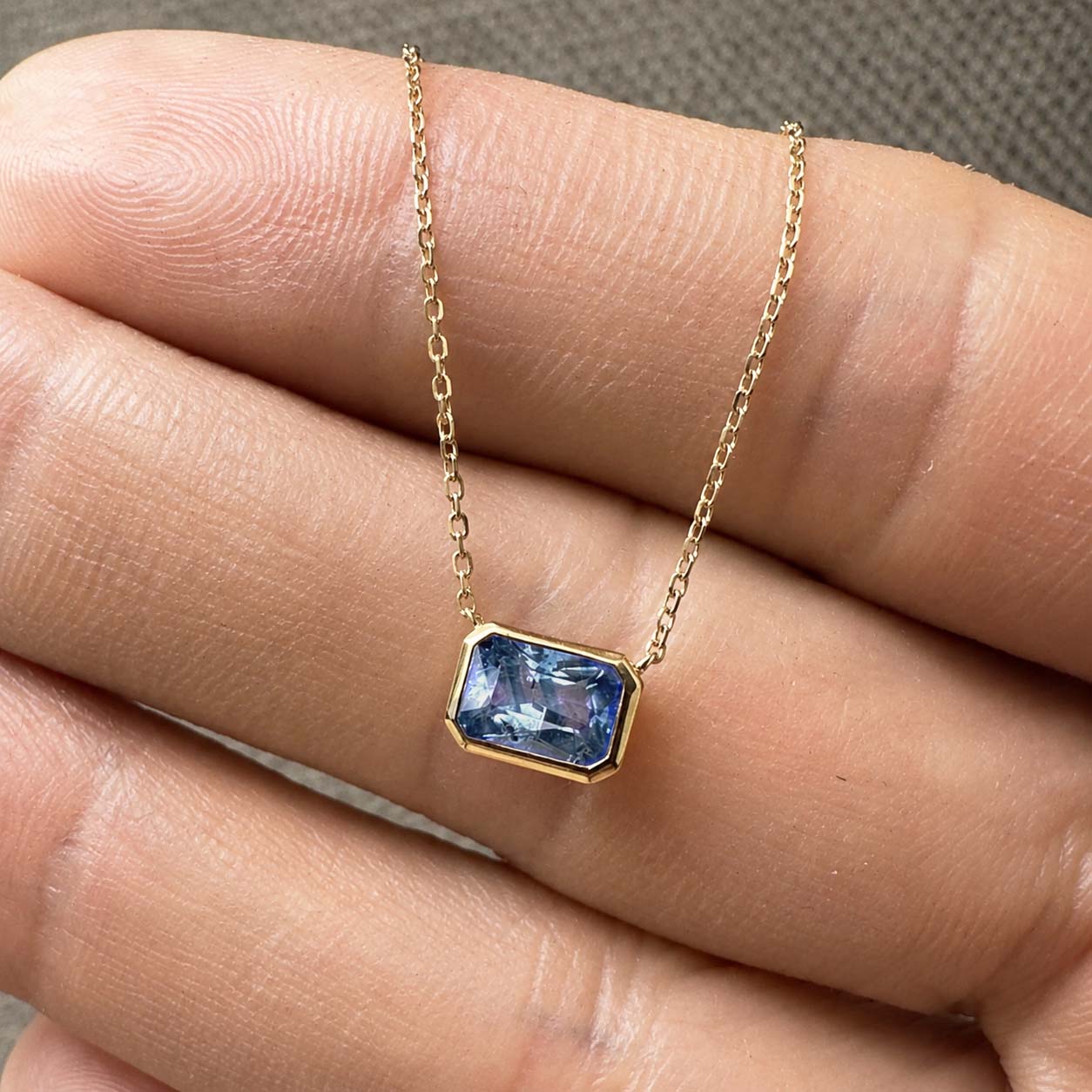 love more bezel set bi-color blue sapphire necklace in 18k gold on hand
