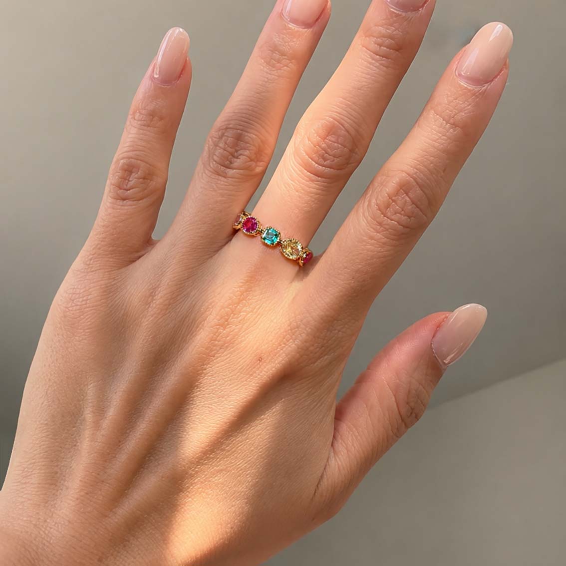 mixed cut colored gemstones ring in 18k gold on hand