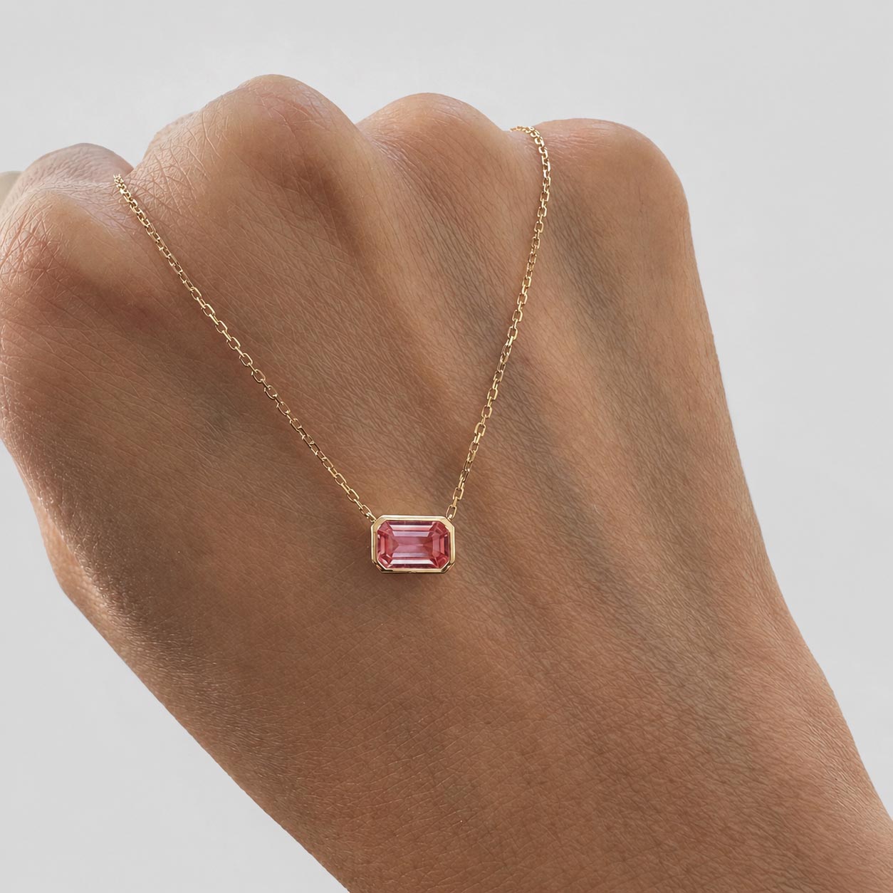 ooak bezel set padparadscha sapphire necklace in 18k gold on hand
