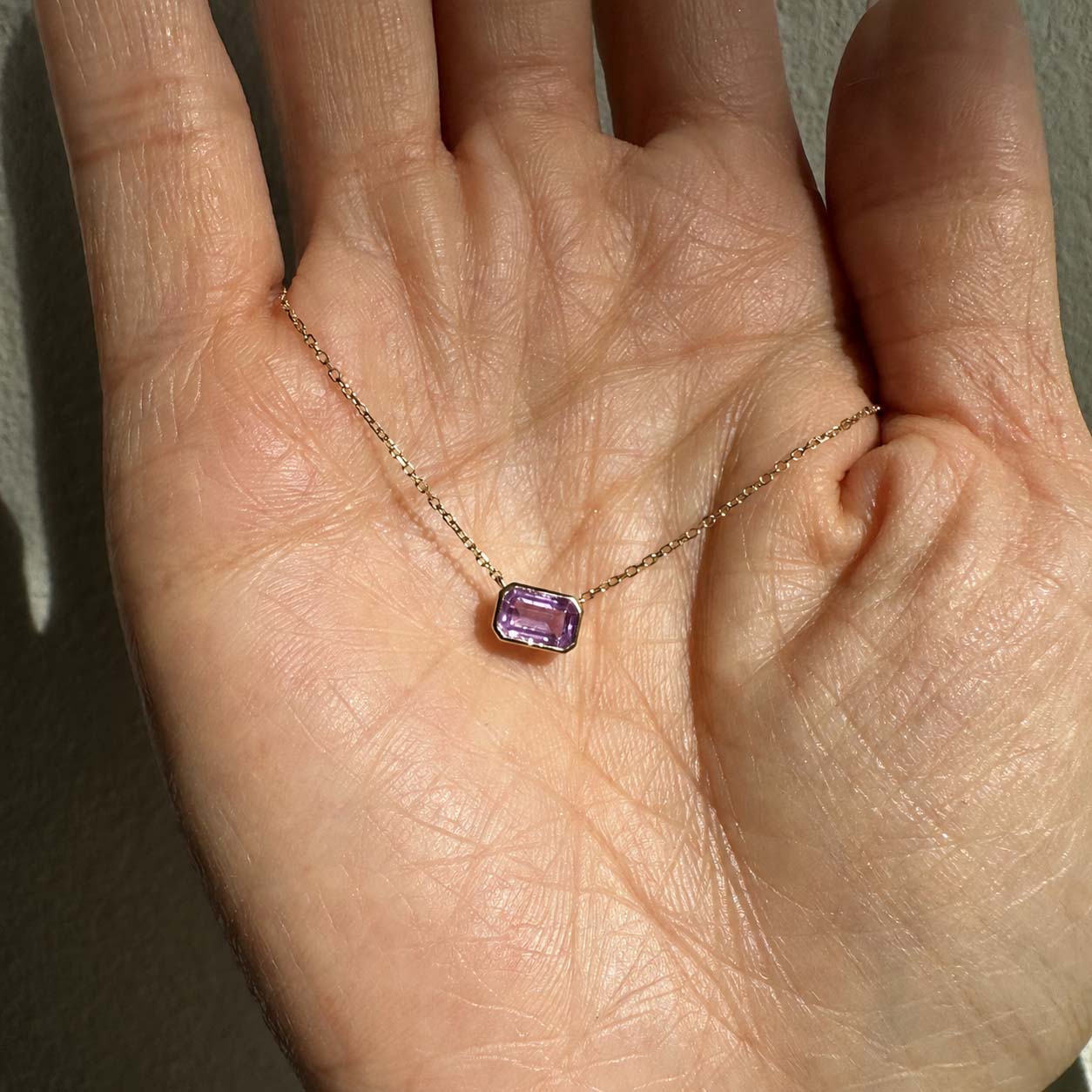 ooak bezel set purple sapphire necklace in 18k gold on hand