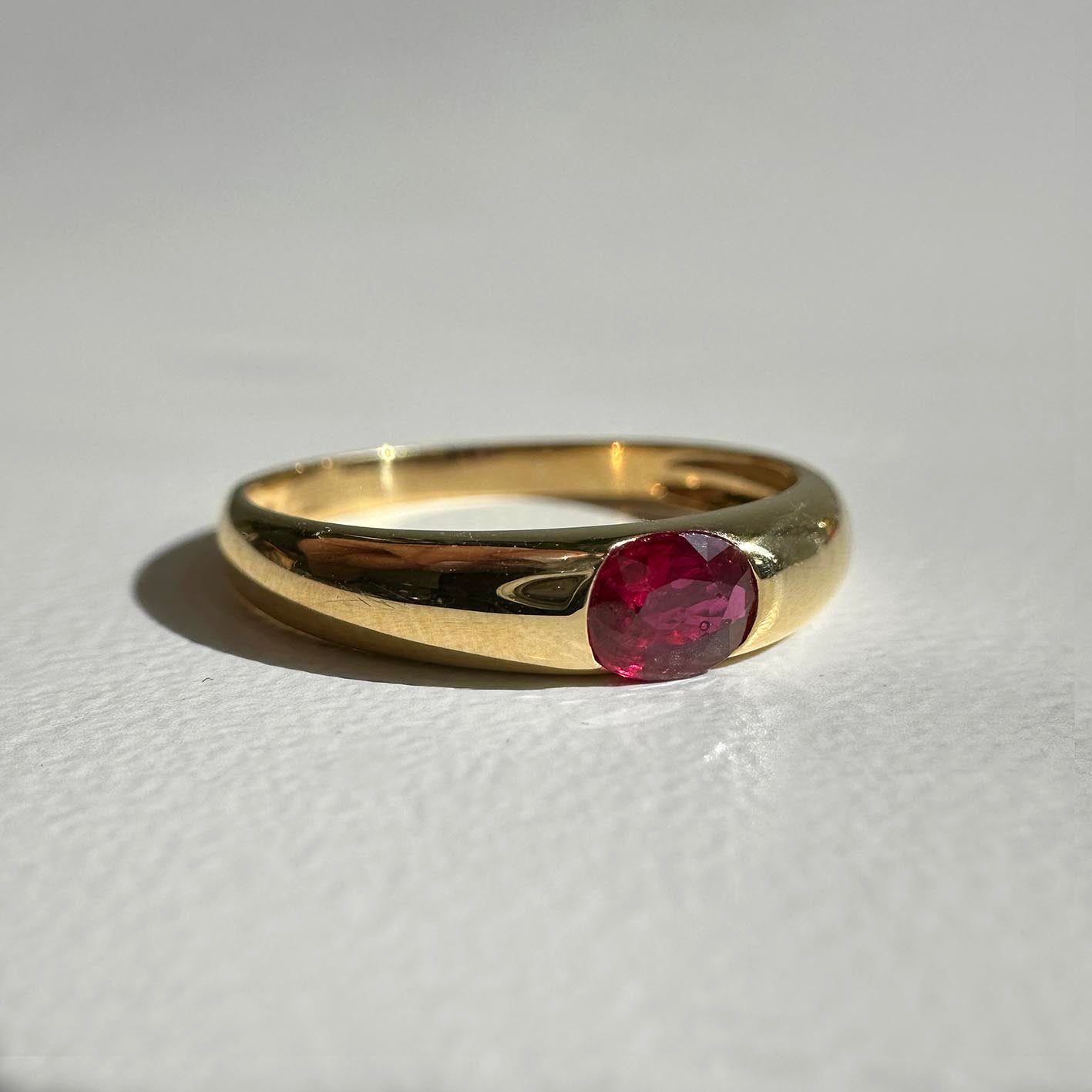 single tulip oval ruby ring in 18k gold on table